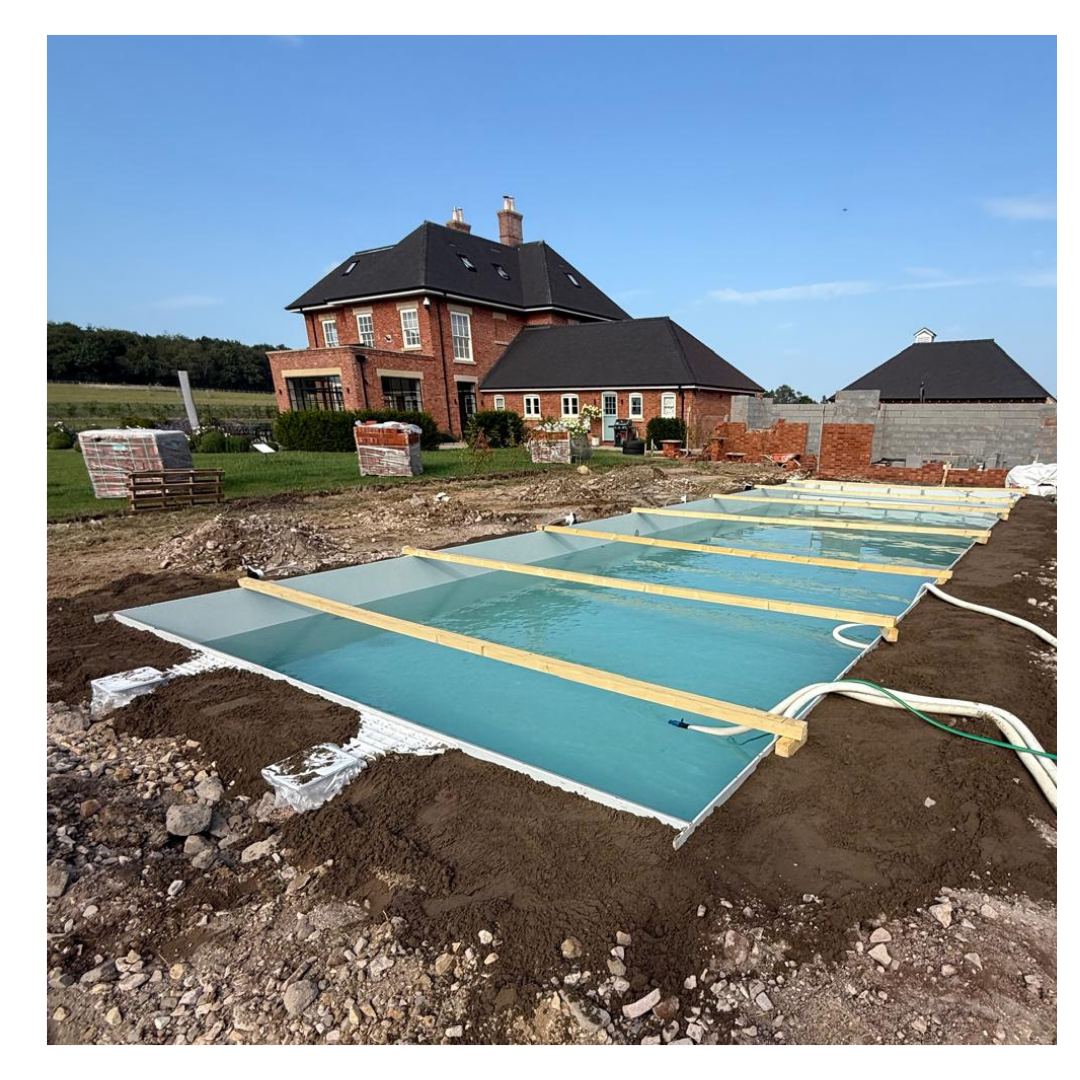 Completed 14m x 5m outdoor pool filled with water in front of a large country house